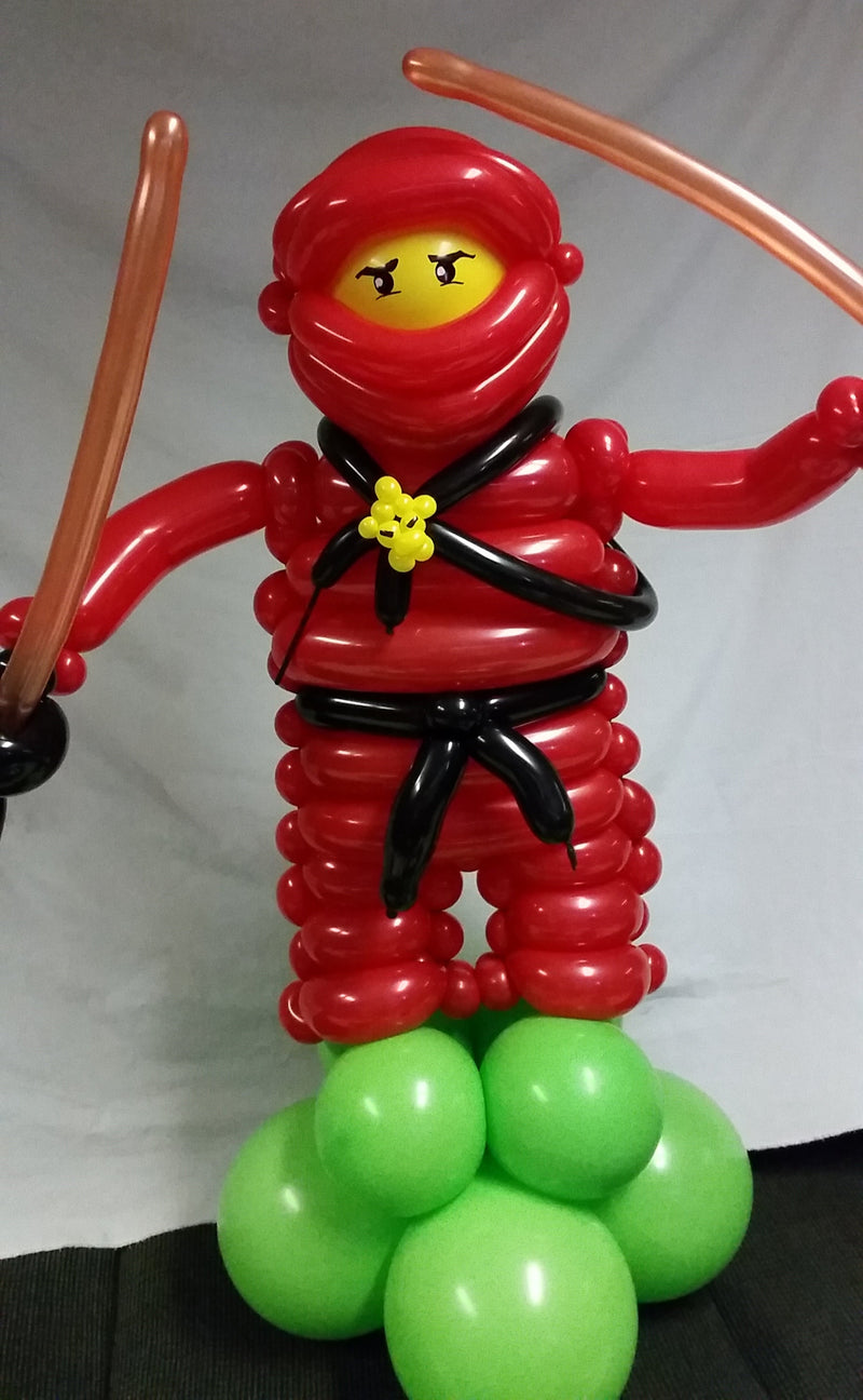 Balloon sculpture of a caterpillar with red, green, and black balloons on a plain background19
