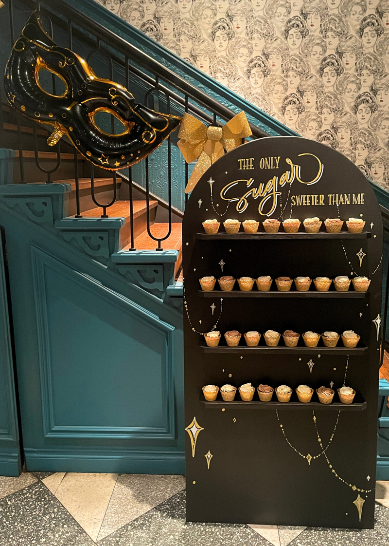 cupcake wall on a black panel with shelves for birthday celebration8