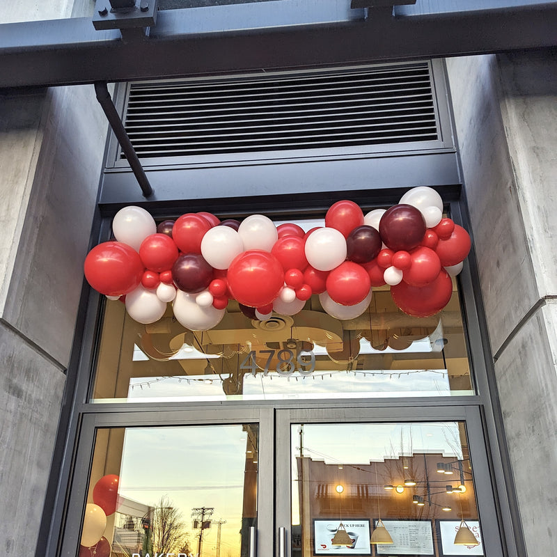 red and white organic balloon garland hanging above cafe entrance 7