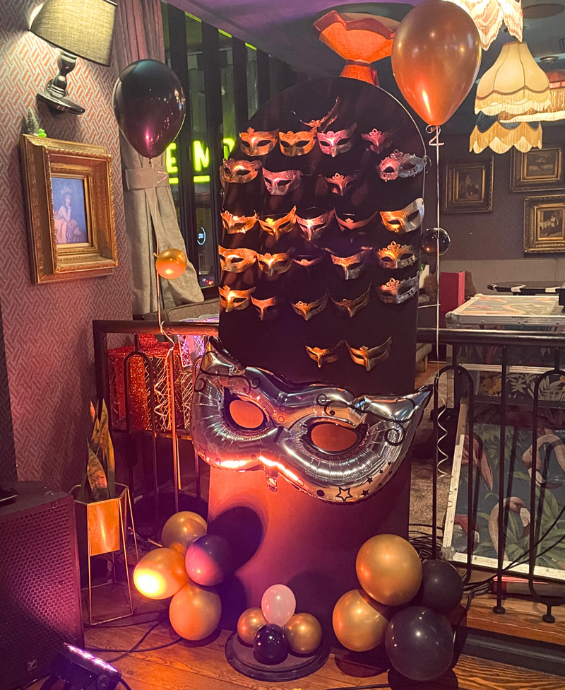 a black panel with masks and black and gold balloons around10