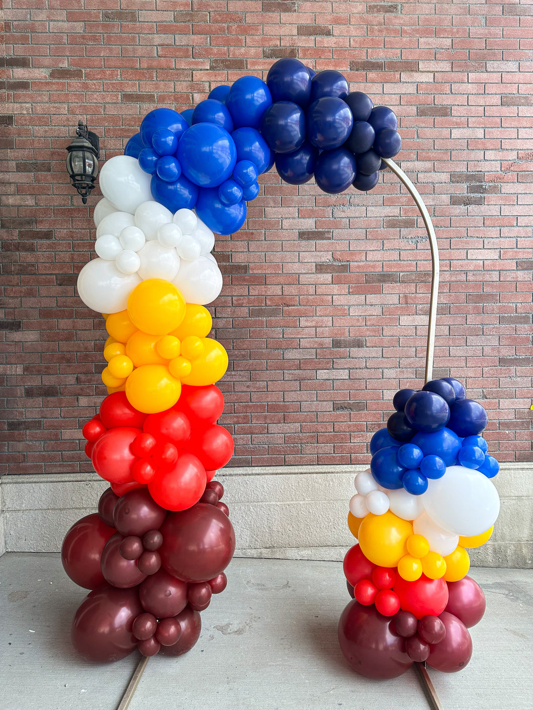 doorway balloon arch in superman colours in front of brick wall