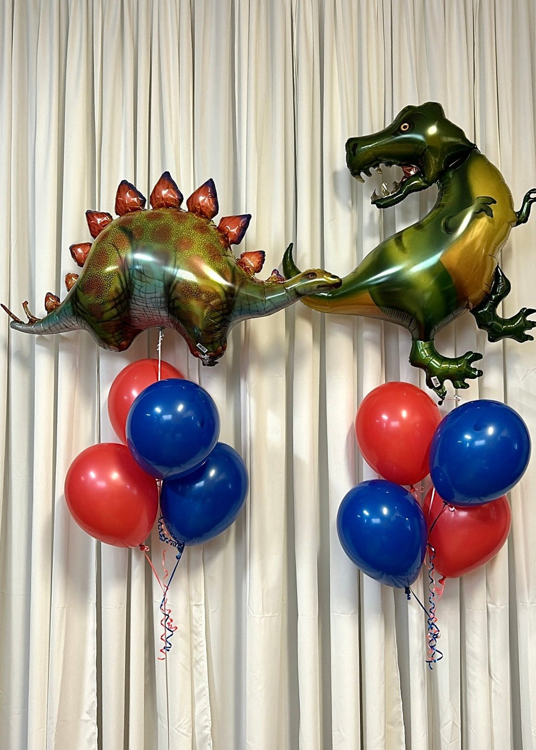 dinosaur balloons on top with blue and red balloons at the bottom