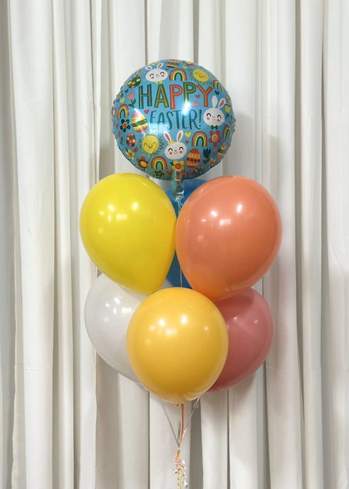 A vibrant Easter balloon bouquet featuring pastel latex balloons in yellow, peach, pink, white, and blue, topped with a festive 