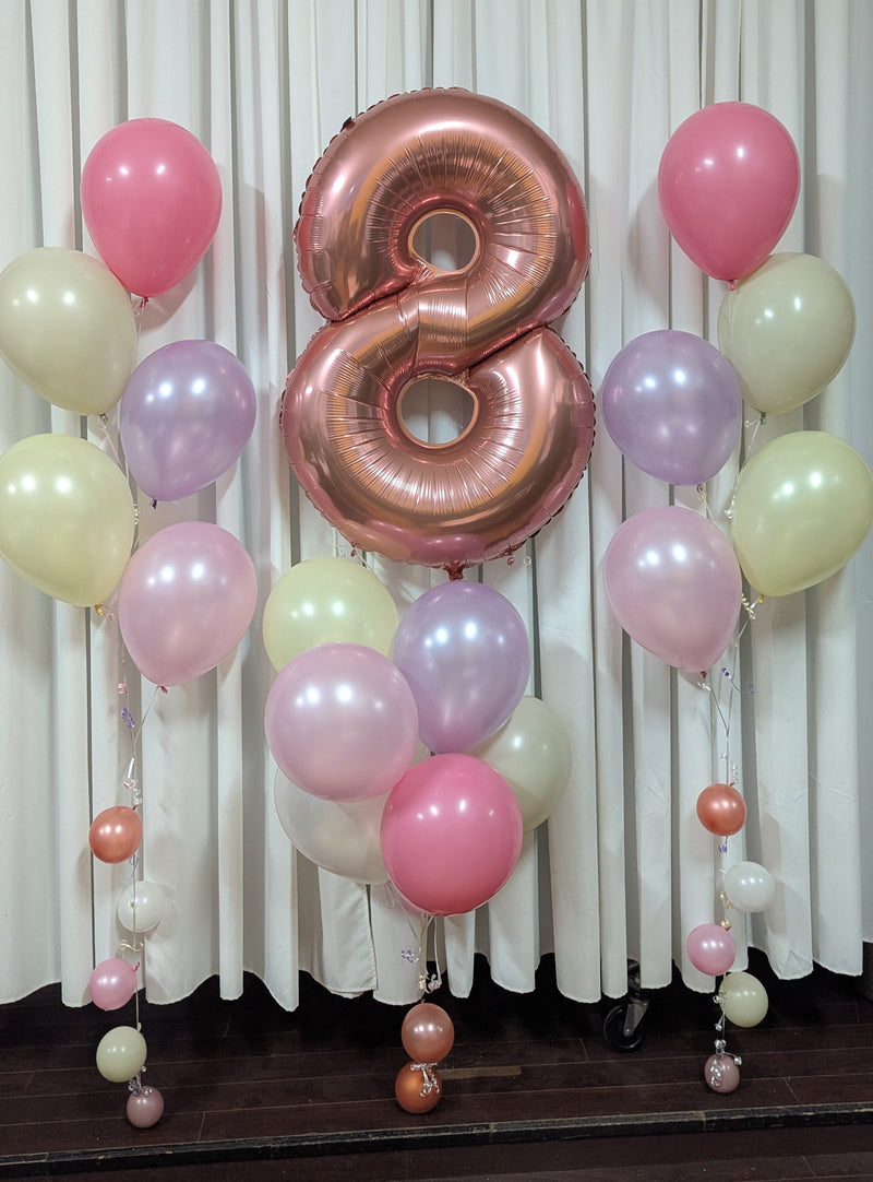 Decorative balloon setup with a large number '8' balloon against a white curtain background.20