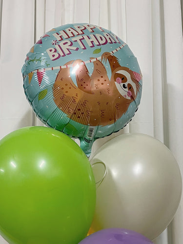 A bouquet of balloons featuring a happy birthday message with a cute sloth design, accompanied by balloons in various colors including green, gray, yellow, purple, pink, and blue.