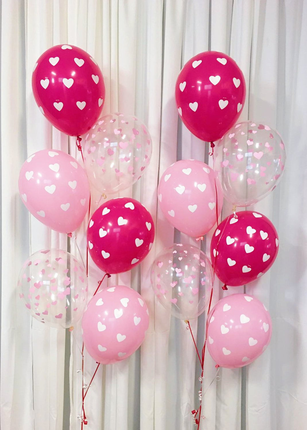 2 bouquets of pink and clear heart balloons in cascading pattern